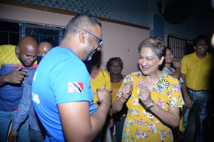 UNC Political Leader, Kamla Persad Bissessar, left, interacts with a supporter after the party’s Monday night meeting.