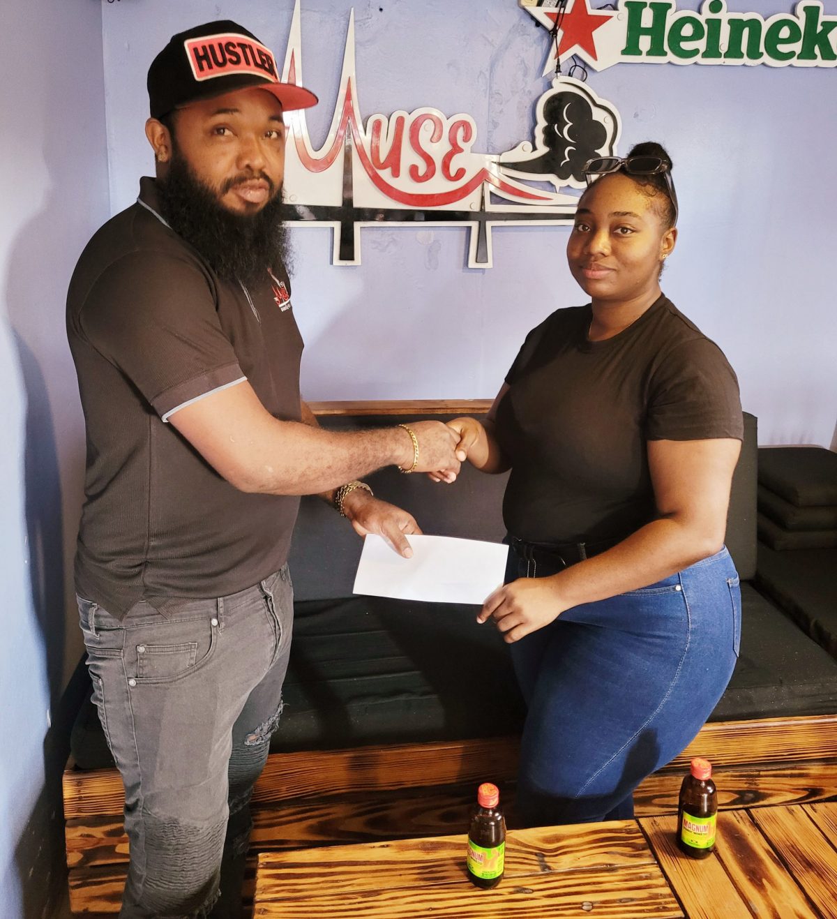 Supervisor of Muse Hookah Bar, Kevin ‘Chelsea’ Evans (left), hands over the sponsorship cheque to Khashana Yhap
