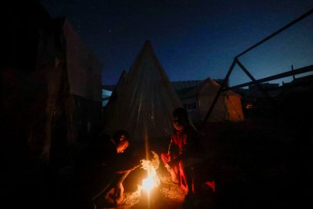 Palestinians who fled their houses due to Israeli strikes sit by a tent, amid the ongoing conflict between Israel and the Palestinian Islamist group Hamas, in Rafah, in the southern Gaza Strip, January 1, 2024. REUTERS/Mohammed Salem