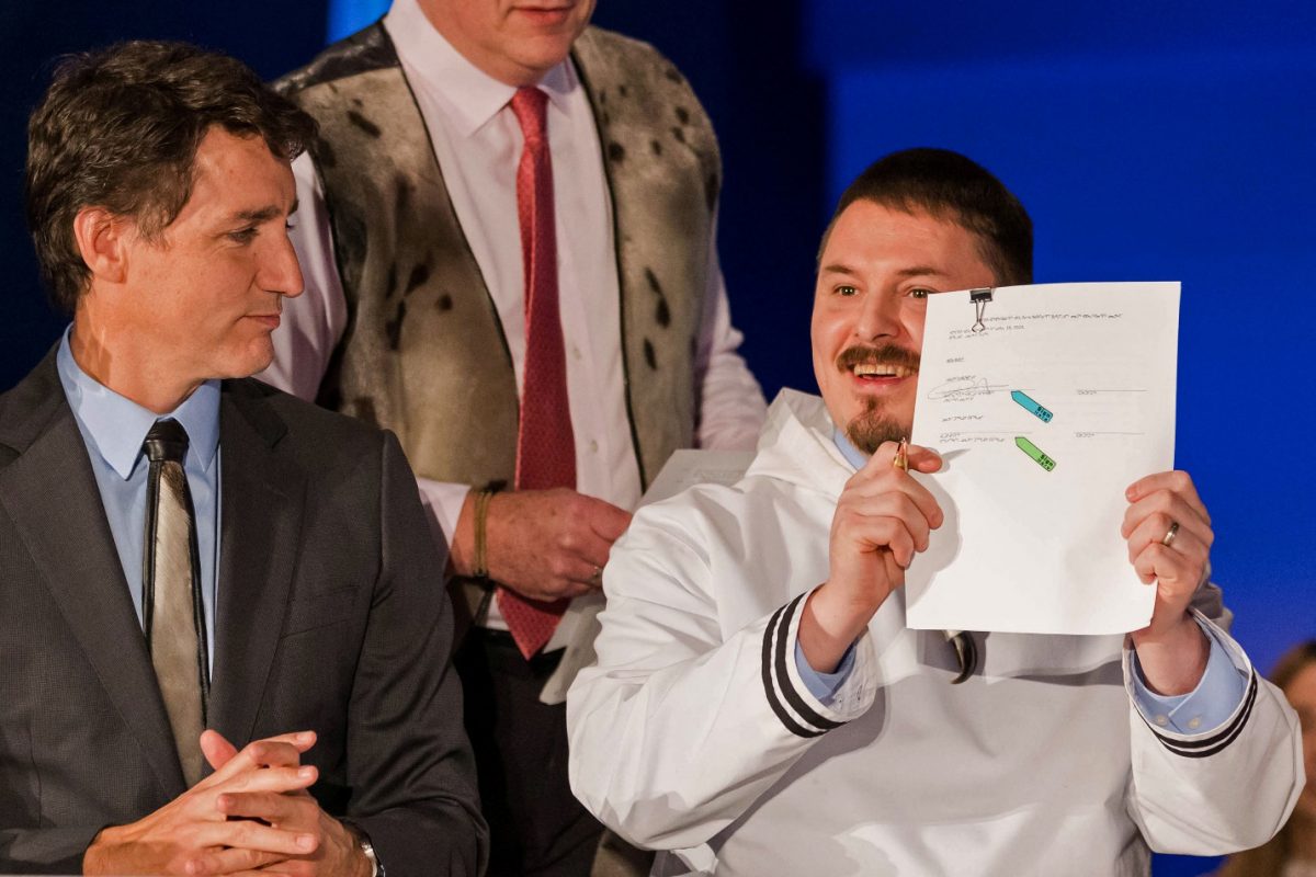 Nunavut Premier P. J. Akeegok holds the signed Nunavut devolution agreement beside Canada’s Prime Minister Justin Trudeau during the ceremony at the Aqsarniit Hotel & Conference Centre in Iqaluit, Nunavut, Canada January 18, 2024. REUTERS/Natalie Maerzluft