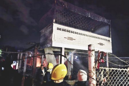 Firemen working to douse the fire at the house where the teacher perished (Guyana Fire Service photo)