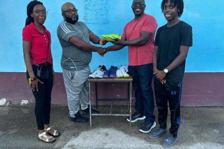 Upper Demerara Athletics Club coach Johnny Gravesande (second from left) receives the athletic gear from Martin McDougal
