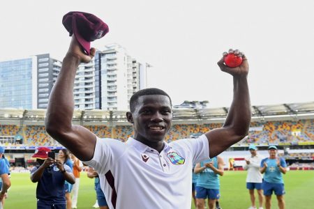 West Indies' Shamar Joseph raises the ball after taking 7 wickets in his team's defeat of Australia on the 4th day of their cricket test match in Brisbane, Sunday, Jan. 28, 2024. (Jono Searle/AAP Image via AP)