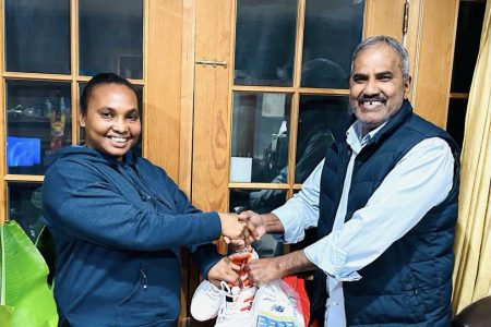 Farida Gayadin (left), mother of Akeem Persaud, receives the donation from Derek Kallicharran of the ‘Cricket Gear for Young and Promising Cricketers in Guyana’ project.