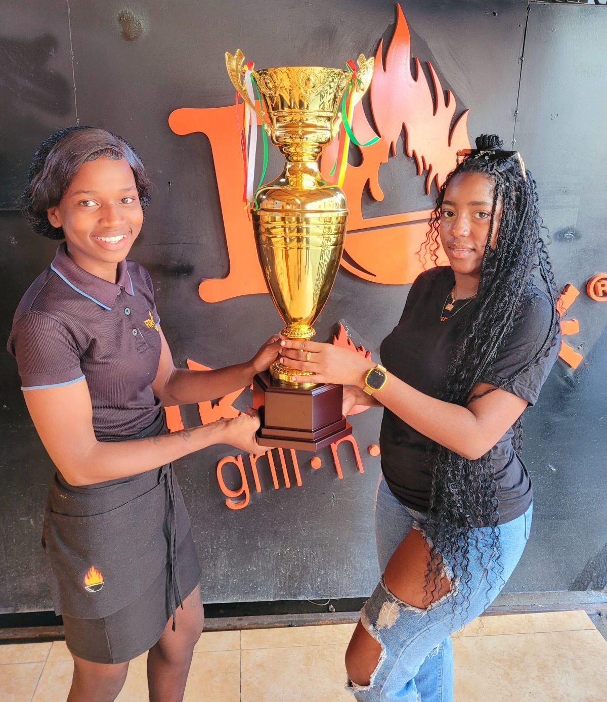 Fireside Grill representative Ashanti Robinson (left) presents the championship trophy to Mash Street-ball Championship Brand Ambassador Terryann Caesar.