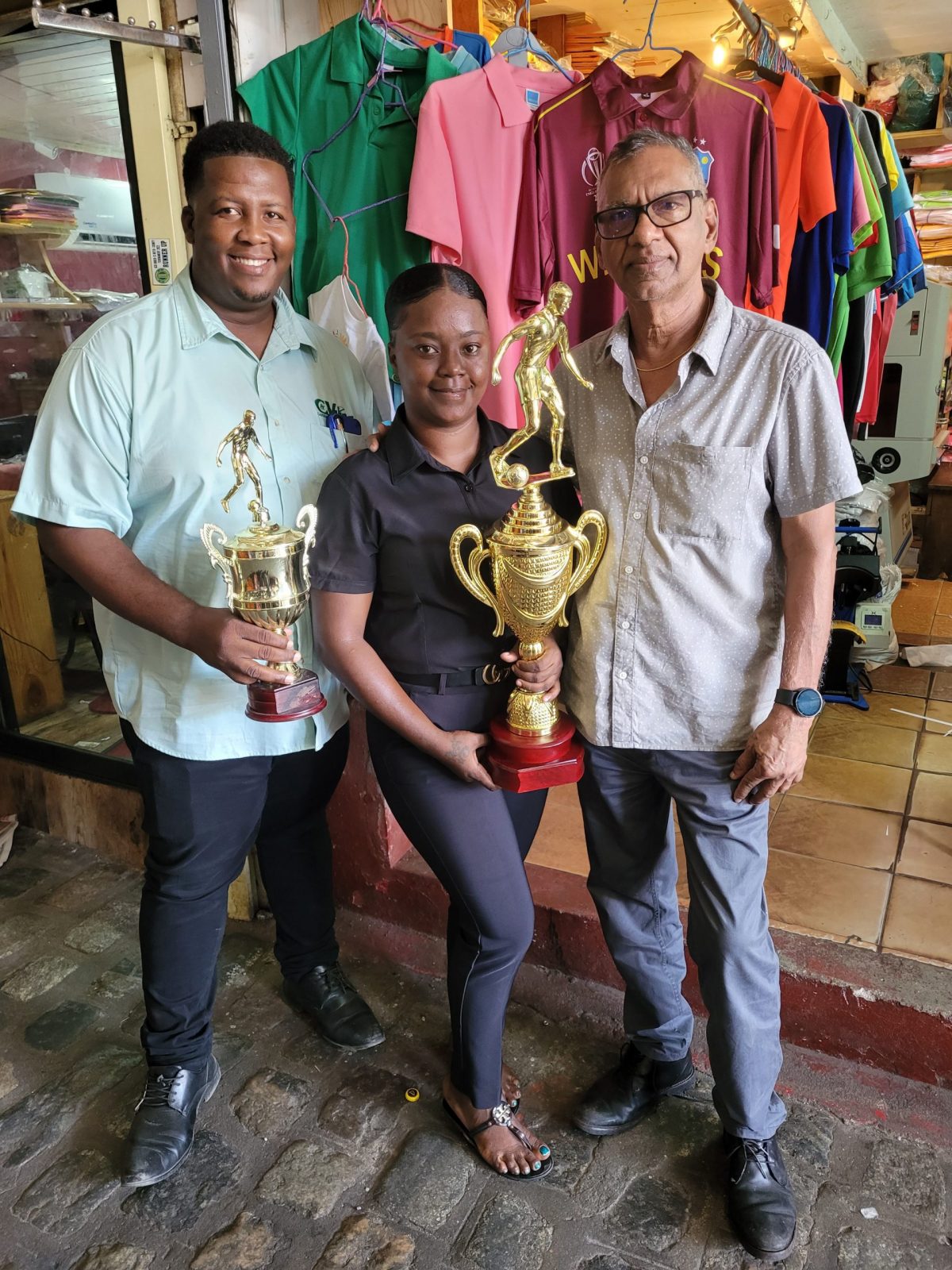 Samarca Evelyn of Sports Management Inc. displaying the second-place accolade alongside Cedric Payne (left) of Cedric Imports and Ramesh Sunich (right) of Trophy Stall.