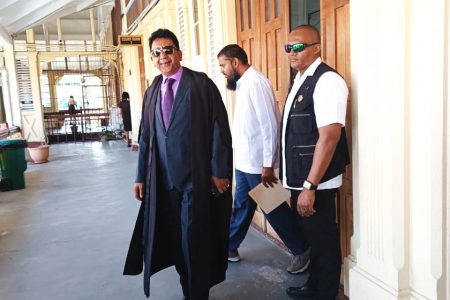  Anil Nandlall (SC) (left) and Saddam Hussain (centre in background) as they exited the courtroom at the High Court yesterday afternoon.
