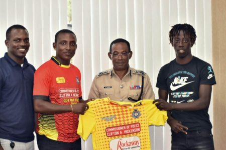 Commissioner of Police Clifton Hickens (2nd from right) presents the team jersey to Captain of the Back Circle Stephon Daniels in the presence of teammates Selwyn Williams (left) and Simeon Moore