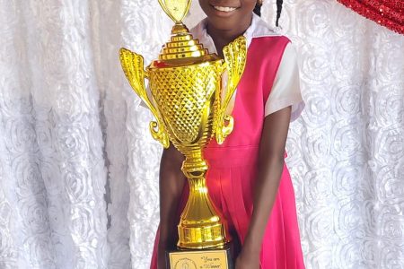 A radiant Ezika Minty after a well-wisher came forward yesterday and provided her with a trophy and other items for her performance in the children’s Mashramani calypso contest. Ezika was controversially disqualified as her rendition about the government’s 6.5% wage increase was deemed to be “not age appropriate” under the rules of the Allied Arts Unit of the Ministry of Education. She had been allowed to sing the calypso in several rounds before being disqualified. The disqualification decision has sparked outrage and raised concerns about her freedom of expression being infringed upon. (GTU Facebook page photo)
