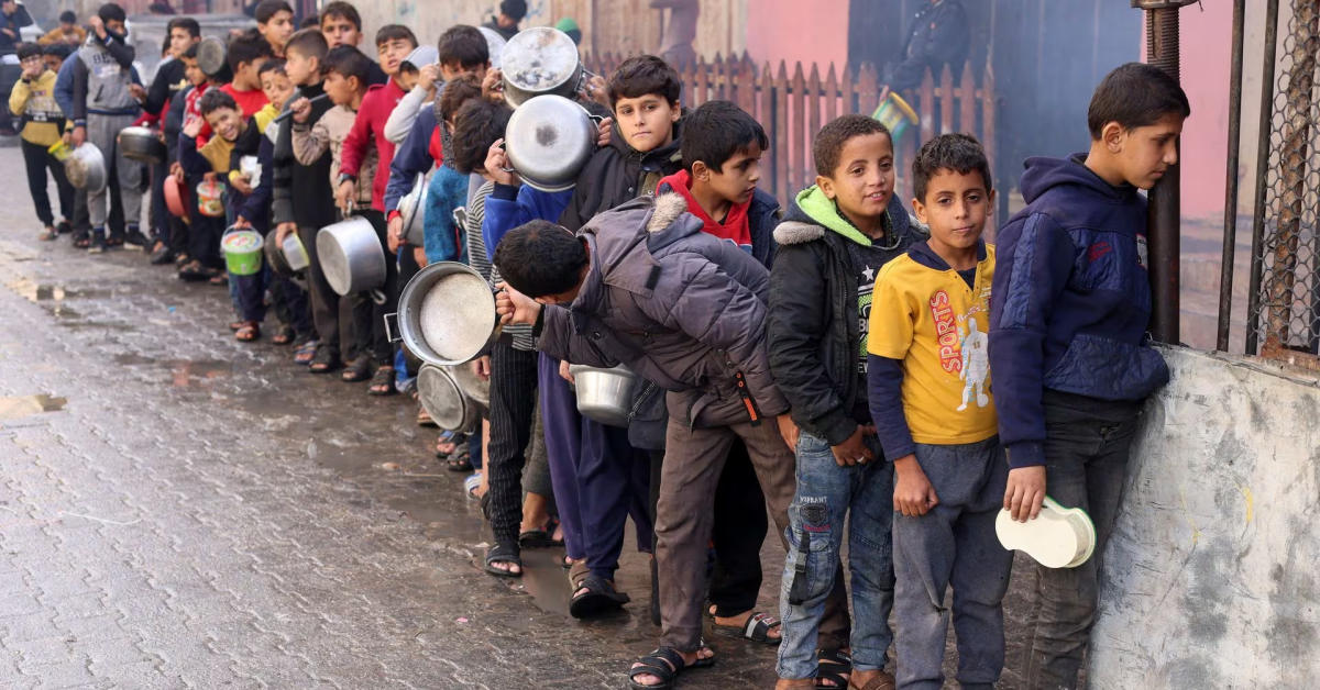 Palestinian children carry pots as they queue to receive food cooked by a charity kitchen, amid shortages in food supplies, as the conflict between Israel and Hamas continues, in Rafah in the southern Gaza Strip December 14, 2023. REUTERS/Saleh Salem