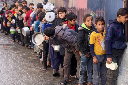 Palestinian children carry pots as they queue to receive food cooked by a charity kitchen, amid shortages in food supplies, as the conflict between Israel and Hamas continues, in Rafah in the southern Gaza Strip December 14, 2023. REUTERS/Saleh Salem