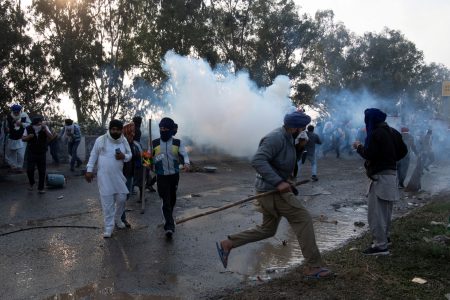 Farmers, who are marching towards New Delhi to press for the better crop prices promised to them in 2021, run for cover amidst tear gas smoke fired by police to disperse them at Shambhu, a border crossing between Punjab and Haryana states, India, February 13, 2024. REUTERS/Rohit Lohia/File Photo