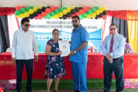 President Irfaan Ali (second from right hands over a land title to a resident as the Attorney General and Minister of Legal Affairs Anil Nandlall, SC (left) and another official look on (DPI photo)