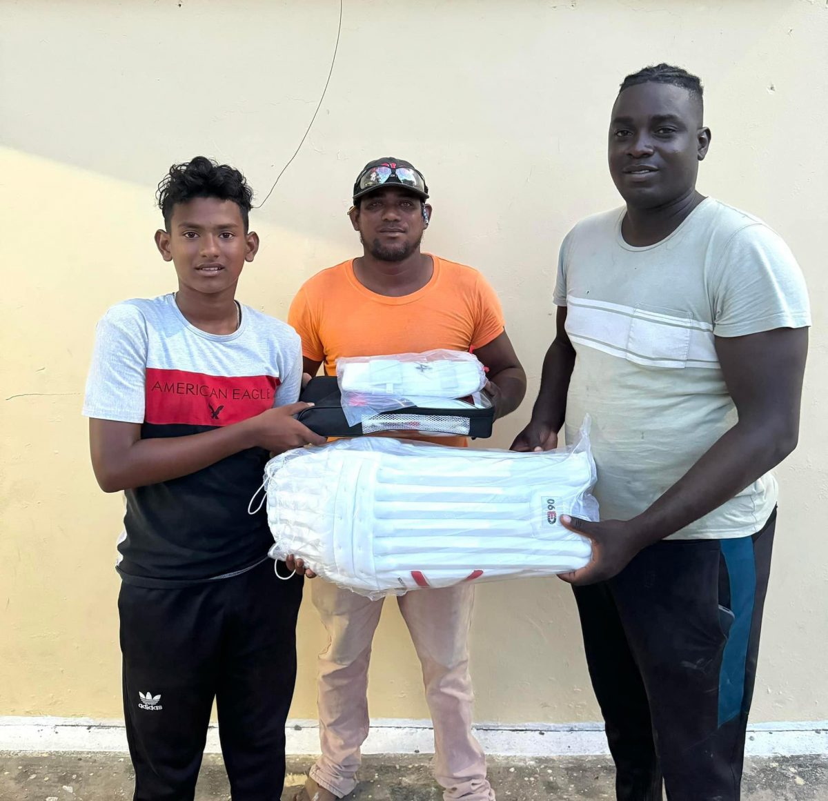 National U-15 player Gilbert Griffith Jr. (left) receiving the equipment from a member of the Tucber Park Cricket Club of New Amsterdam, Berbice
