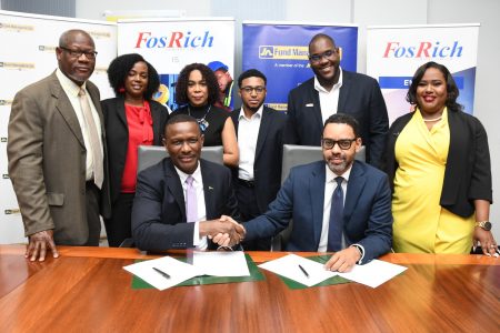 Cecil Foster (sitting at left), Chief Executive Officer of FosRich Company Ltd shakes hands with Brandon Hayden, Managing Director of JN Fund Managers Ltd following a signing agreement to formalise the successful execution of J$900 million bond raise for FosRich Company Ltd.  (JN Group photo)