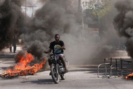 A man drives past a burning barricade during a protest against Prime Minister Ariel Henry's government and insecurity, in Port-au-Prince, Haiti March 1. REUTERS/Ralph Tedy Erol