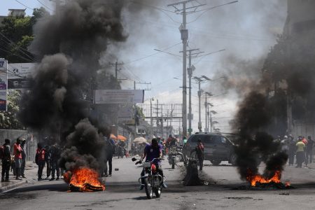 Motorists pass by a burning barricade during a protest as the government said it would extend a state of emergency for another month after an escalation in violence from gangs seeking to oust the Prime Minister Ariel Henry, in Port-au-Prince, Haiti, March 7, 2024. REUTERS/Ralph Tedy Erol