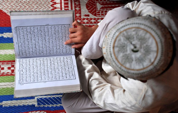 FILE PHOTO: A Muslim boy reads the Koran at a madrasa or religious school on the first day of the holy month of Ramadan in the northern Indian city of Mathura August 23, 2009. REUTERS/K. K. Arora/File Photo