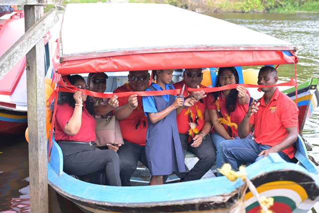  The community of 27 Canal Bank, Matarkai sub-district, yesterday received a boat and  engine to the tune of $3.5M. According to the Department of Public Information (DPI) the boat and engine will enable the students to attend school more regularly and punctually. In this photograph a student cuts the ribbon to officially commission the boat while Minister of Housing and Water, Collin Croal and Minister of Local Government and Regional Development, Sonia Parag along with other officials look on. (DPI photo)
