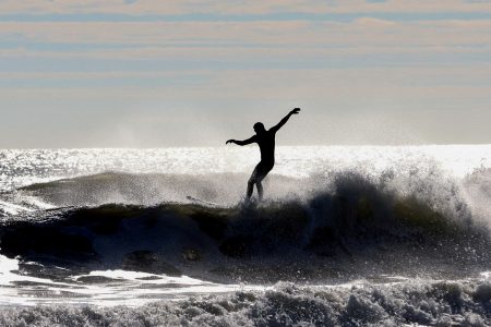 FILE PHOTO: A surfer rides a wave in the Atlantic Ocean off Belmar, New Jersey, U.S., November 27, 2023. REUTERS/Mike Segar/File Photo