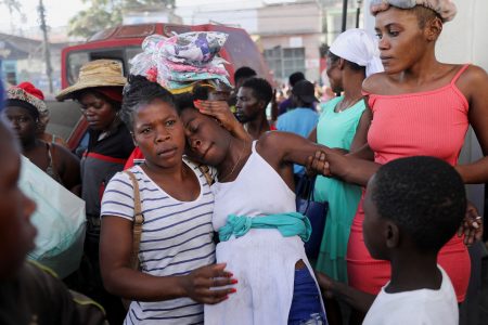 A woman is comforted by others at a crime scene where the bodies of several people, who had been shot dead earlier in the morning amid an escalation in gang violence, were being removed by an ambulance, in Port-au-Prince, Haiti March 18, 2024. REUTERS/Ralph Tedy Erol