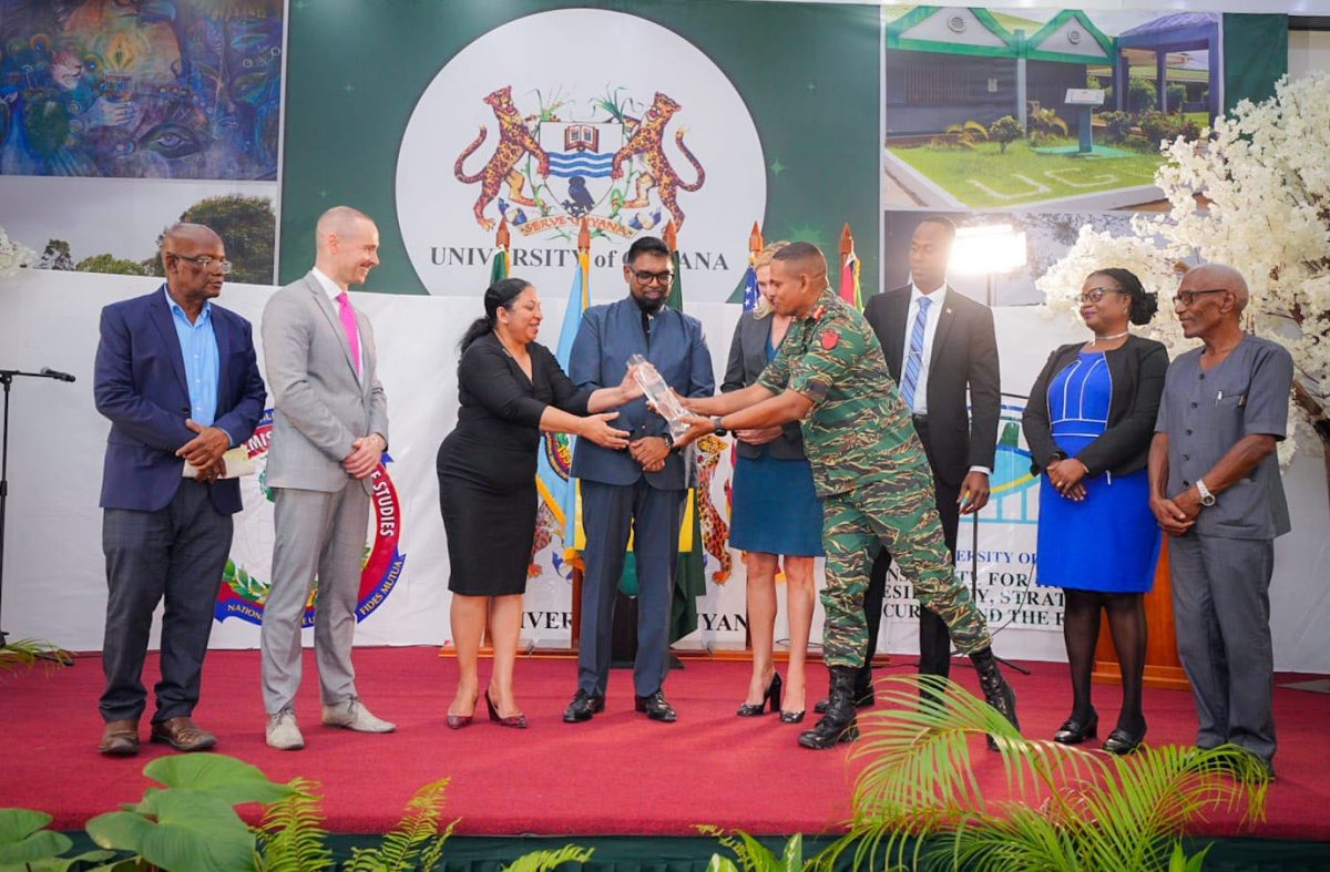 The award being presented to UG Vice Chancellor, Dr Paloma Mohamed by Chief of Staff of the Guyana Dafence Force, Omar Khan. President Irfaan Ali is fourth from left.  (Office of the President photo)