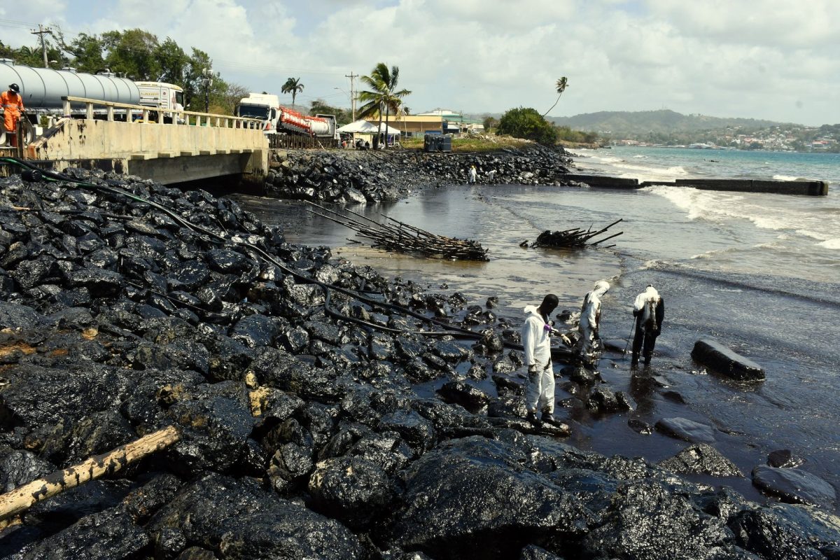 Workers use a vacuum hose to collect oil that was being pumped into trucks on site at Lambeau, Tobago, on Monday.