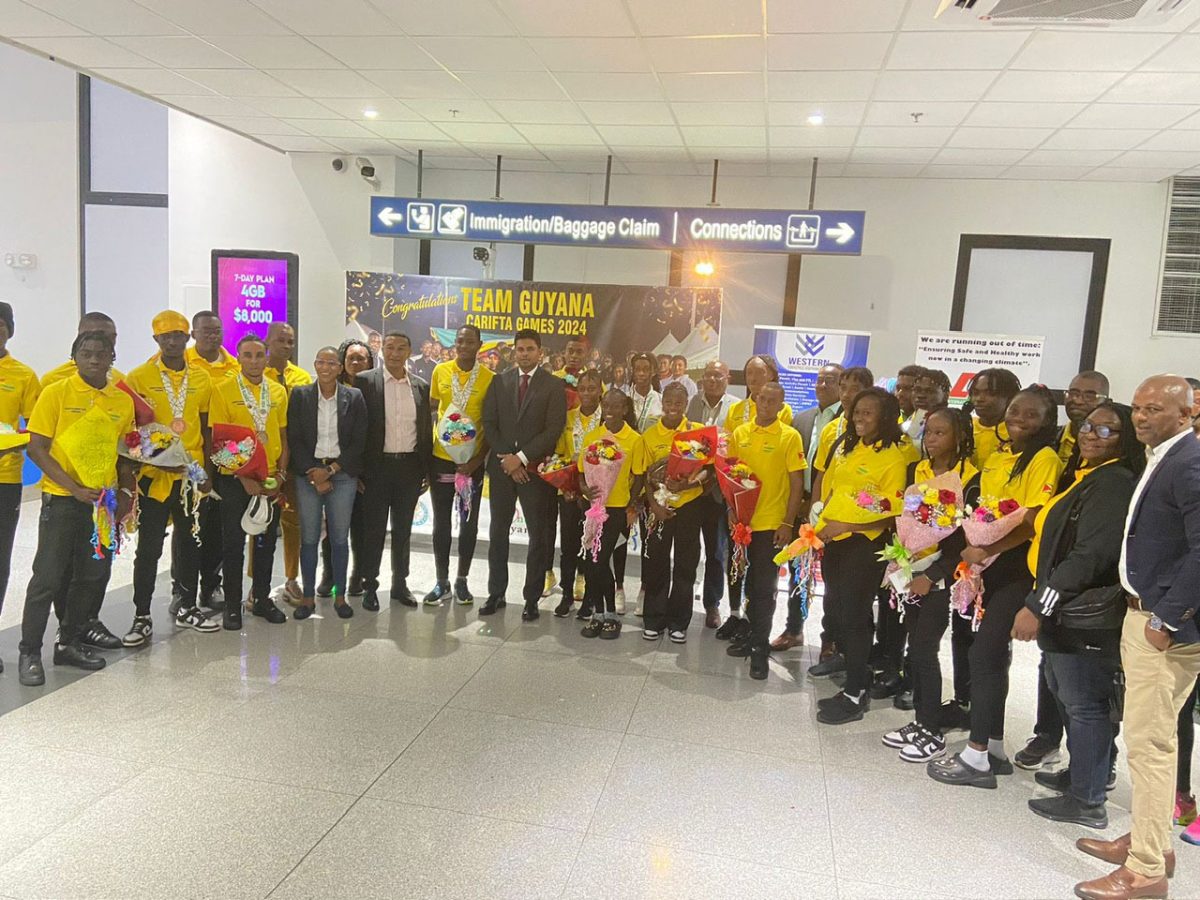 Minister of Culture, Youth, and Sports, Charles Ramson Jr., along with other NSC officials, pose with the returning Carifta Games contingent at the CJIA
