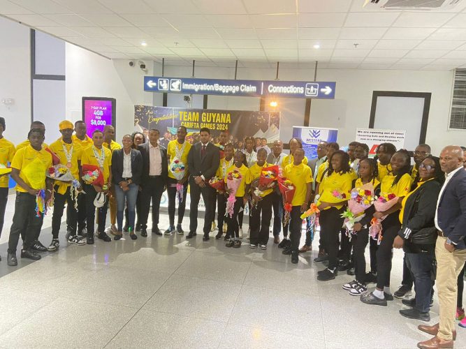 Minister of Culture, Youth, and Sports, Charles Ramson Jr., along with other NSC officials, pose with the returning Carifta Games contingent at the CJIA
