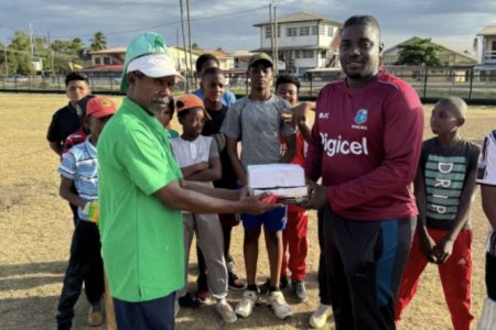 Floyd Benjamin (left) presents the balls on behalf of ‘Project Cricket Gears’ organisation to Tucber Park member Orlando Tanner in the presence of young players.
