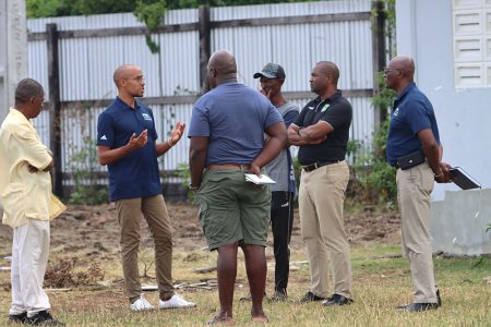 FIFA’s Regional Office Lead, Hervé Blanchard (2nd from left), makes a point to officials, including GFF President Wayne Forde (2nd from right), at the Anns Grove ground