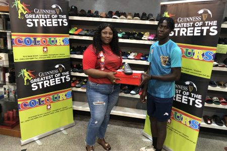 Laing Avenue’s Bevney Mark, the MVP of the Guinness ‘Greatest of the Streets’ Georgetown Championship, receives his prize from Safisha Hope, Supervisor of Colours Boutique