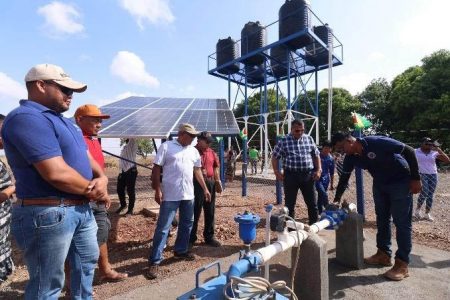 Minister of Housing and Water Collin Croal and other officials watch on as the solar-powered pump for the well is being tested.
