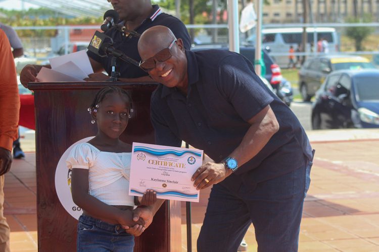 Director of Sport Steve Ninvalle hands
over a Certificate of Participation to one
of the youngest participants in the NSC’s ‘Easter Learn to Swim’ Programme.