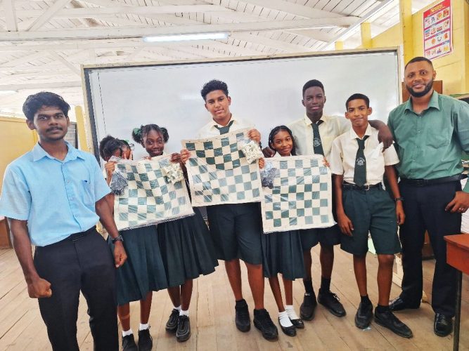 Ricardo Narine poses with some students of Houston Secondary School displaying the chess sets
