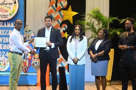 Minister of Culture, Youth and Sport, Charles Ramson Jr (second from left) and members
from the ministry presenting a grant certificate to one of the new recipients. (DPI photo)