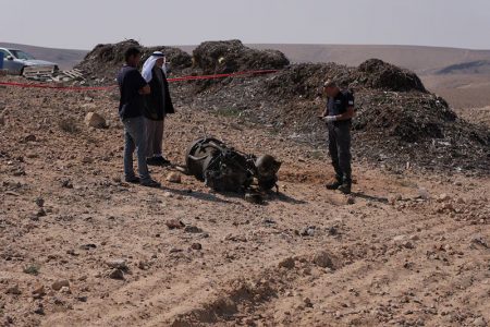 A police officer and residents inspect the remains of a rocket booster that, according to Israeli authorities critically injured a 7-year-old girl, after Iran launched drones and missiles towards Israel, near Arad, Israel, April 14, 2024.