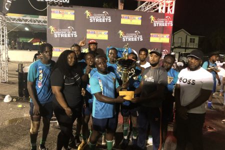 Laing Avenue captain Terrence Nero receives the championship trophy from Guinness Brand Manager Jeoff Clement after capturing the Guinness ‘Greatest of the Streets’ Georgetown Championship for the first time in their history