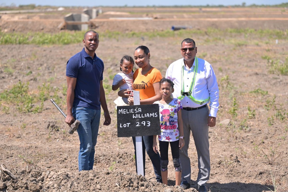 A proud family identifies their lot with Minister of Housing and Water Collin Croal. (CH&PA photo)