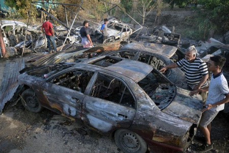 CHARRED CAR: Fire victim Rory Rampersad, right, looks at one of six vehicles destroyed by fire at Maraj Avenue, Mission Road, Freeport, yesterday. —Photo: DEXTER PHILIP 