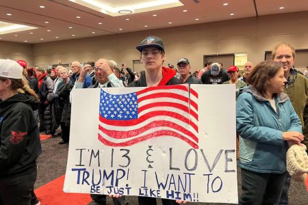 A young Donald Trump supporter holds up a sign at a rally in Green Bay, Wisconsin, April 2, 2024