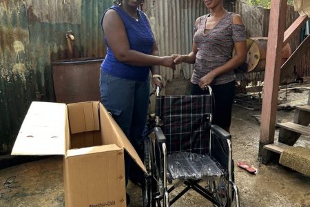 A representative of the Literacy Empowerment Assistance Foundation, hands over two wheelchairs to children in Region 6  