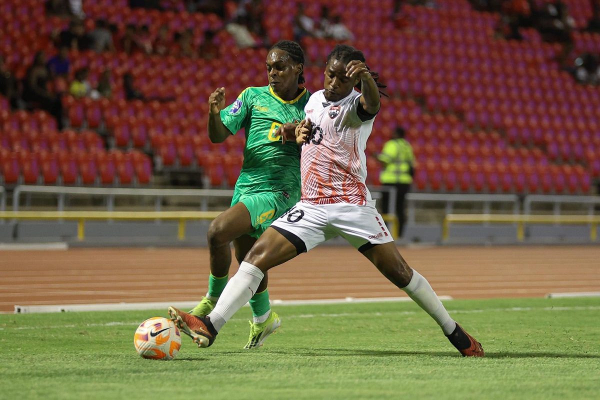 Darron Niles (green) of Guyana battles Duane Muckett of Trinidad and Tobago for possession
