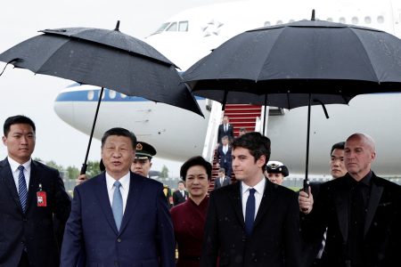 France's Prime Minister Gabriel Attal, China's President Xi Jinping and his wife Peng Liyuan walk under umbrellas upon their arrival for an official two-day state visit, at Orly airport, south of Paris on May 5, 2024. Chinese President Xi Jinping arrived in France on May 5, 2024, for a state visit hosted by Emmanuel Macron where the French leader will seek to push his counterpart on issues ranging from Ukraine to trade.     STEPHANE DE SAKUTIN/Pool via REUTERS