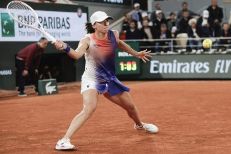 Iga Swiatek returns a ball during a rally against Naomi Osaka