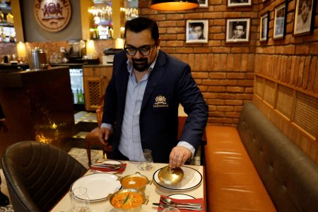 Amit Bagga, CEO of Daryaganj restaurant, shows a freshly prepared butter chicken dish and the lentil dish Dal Makhani inside Daryaganj restaurant at a mall, in Noida, India, January 23, 2024. REUTERS/Sahiba Chawdhary