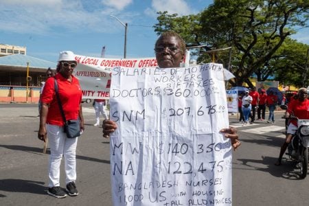  This marcher at yesterday’s May Day parade queried payments to workers in the health sector.