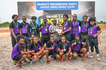 Kuru Kururu ‘A’ Captain, Shervin Henry receives the top prize and trophy from Hon. Minister Kwame McKoy in the presence of his teammate on Sunday afternoon at the Kuru Kuru Ground. 