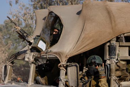 An Israeli soldier gestures while in a military vehicle, amid the Israel-Hamas conflict, near the Israel-Gaza border, in Israel, June 23, 2024.