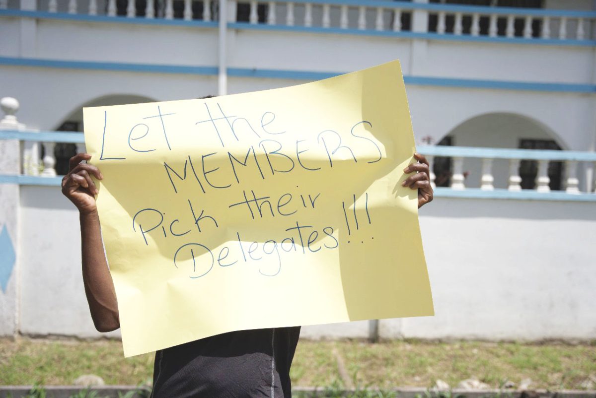 Protestors in front of Congress Place with their placards shielding their faces 